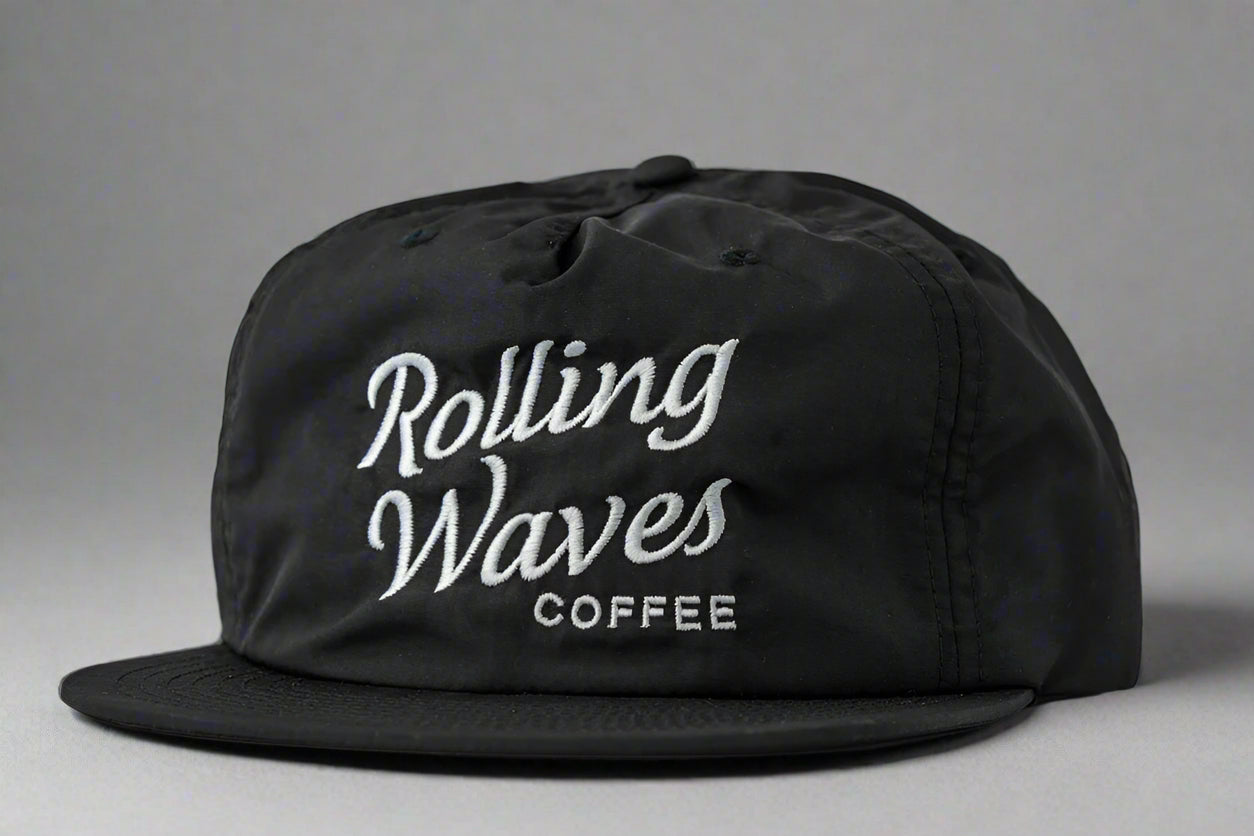 Black cap with 'Rolling Waves Coffee' text on a gray background